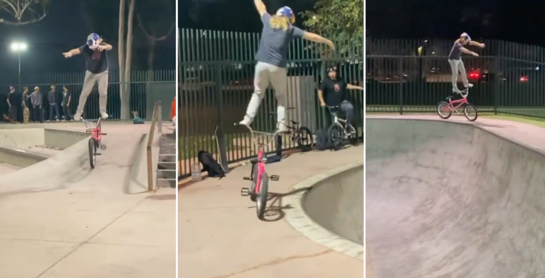 BMX Rider Rides Around Skate Park While Standing Balanced On Handlebars