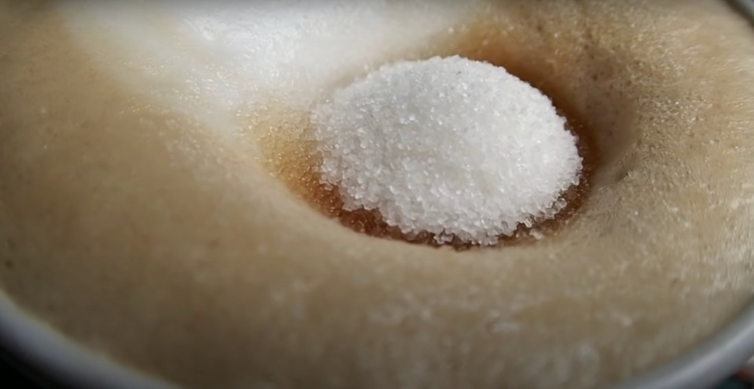 Satisfying Macro View Of Granulated Sugar Sinking Into A Latte